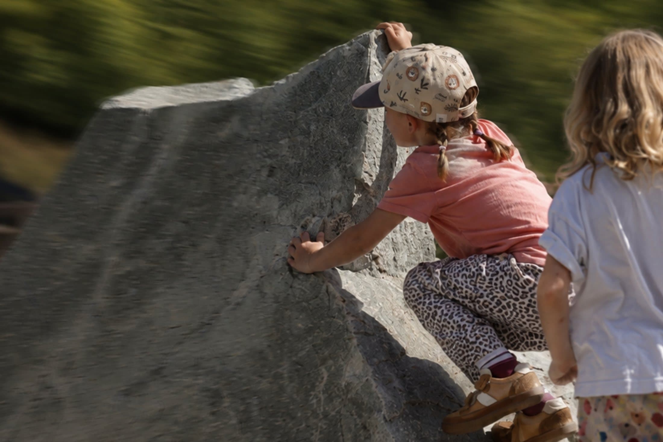 Kind klettert einen Felsen hinauf