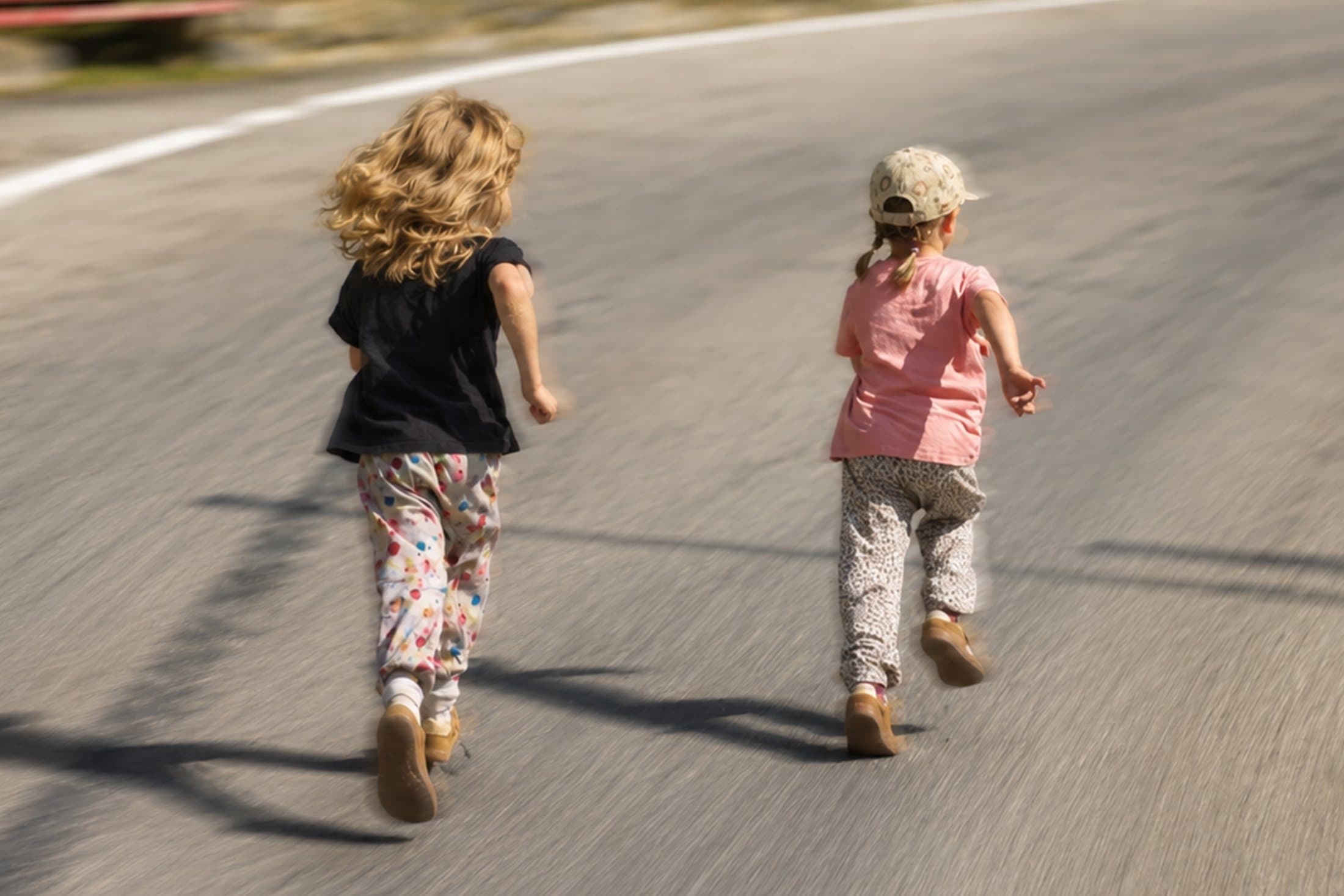 Zwei Kinder rennen eine Strasse hinunter