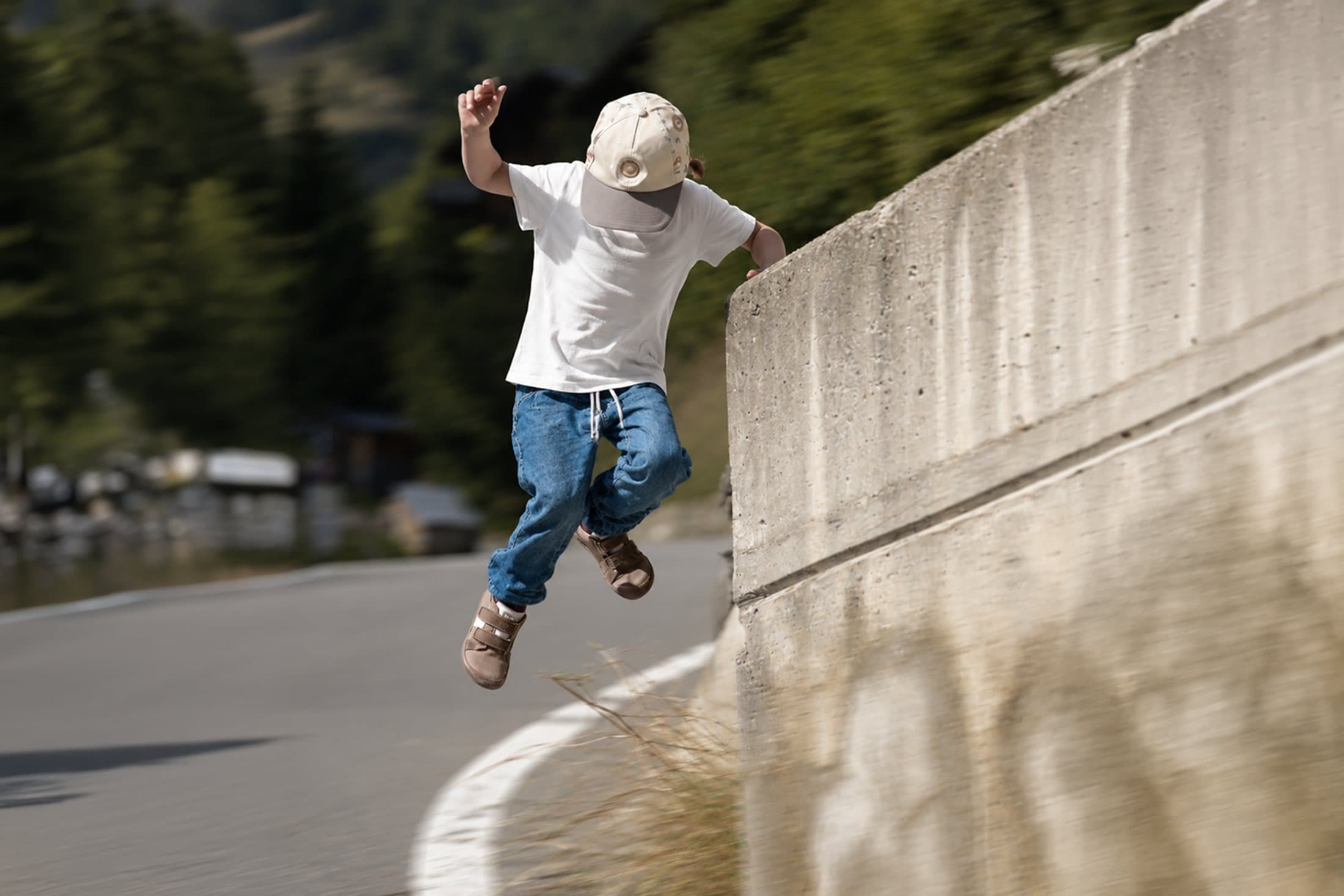 Kind springt von einer Mauer auf die Strasse